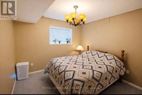 Welland (West Welland) apartment for rent - A bedroom with a patterned bedspread, a window with blinds, a chandelier, and a window air conditioner.