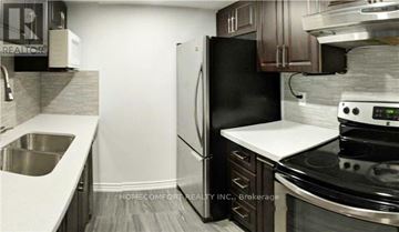 Toronto (Bay Street Corridor) condo for rent - A modern kitchen with a black refrigerator, stove, and white countertops.