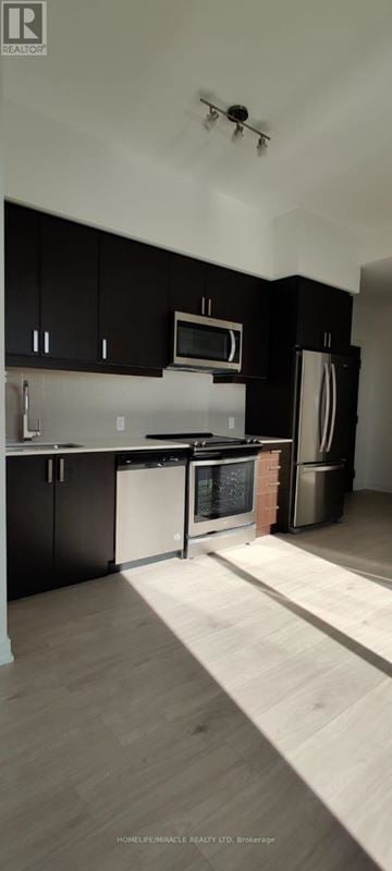 Mississauga (Hurontario) condo for rent - A modern kitchen with black cabinets and a white dishwasher.