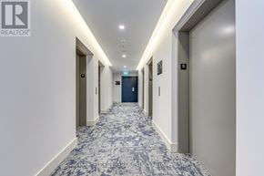 Hamilton (Corktown) condo for rent - A long hallway with doors on both sides and a carpet on the floor.
