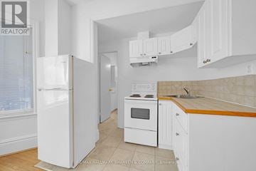 Toronto (Yonge-St. Clair) multi-family for rent - A white kitchen with a refrigerator, oven, and cabinets.