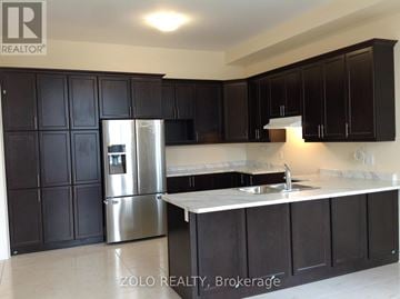 Bradford West Gwillimbury (Bradford) apartment for rent - A kitchen with black cabinets and a stainless steel refrigerator.