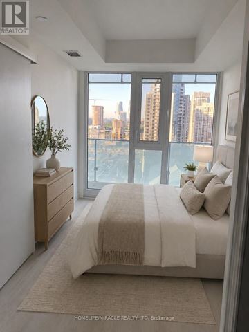 Mississauga (City Centre) condo for rent - A bedroom with a large bed and a view of the city.