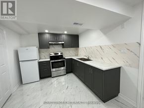 Toronto (Rouge) apartment for rent - A kitchen with black cabinets and a white refrigerator.