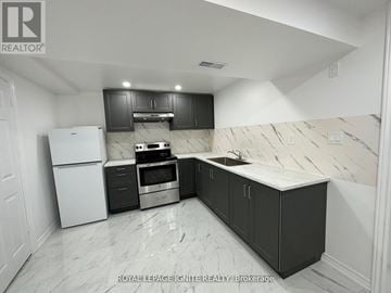 Toronto (Rouge) apartment for rent - A kitchen with black cabinets and a white refrigerator.