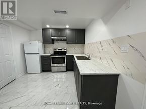 Toronto (Rouge) apartment for rent - A kitchen with a white fridge, black cabinets, and a marble countertop.