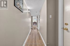 Barrie (East Bayfield) apartment for rent - A hallway with a wooden floor and white walls leading to a door.