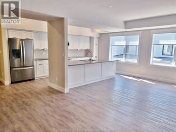 Windsor townhouse for rent - A spacious kitchen with white cabinets and a stainless steel refrigerator.