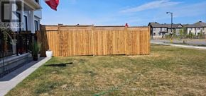 Ottawa apartment for rent - A wooden fence in a yard with a house and other houses in the background.
