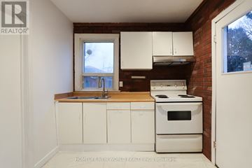 Toronto (Rockcliffe-Smythe) apartment for rent - A kitchen with white cabinets and a brick wall.