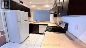 Toronto (Willowdale East) townhouse for rent - A kitchen with a white fridge and black cabinets.