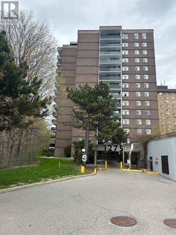 Toronto (Woburn) condo for rent - A tall building with a parking lot in front of it.