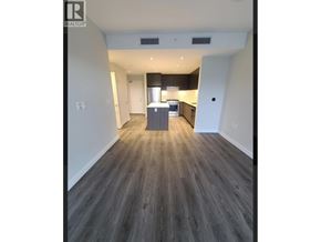 Vancouver apartment for rent - A spacious room with wooden flooring and a kitchen area in the background.