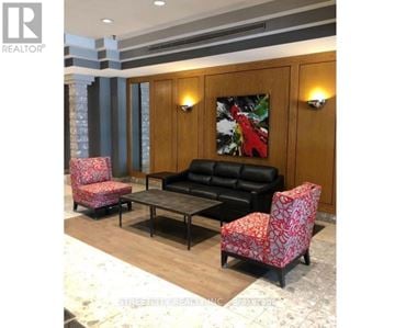 London East (East F) condo for rent - A living room with a black couch, two red patterned chairs, and a coffee table.