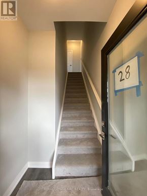 Niagara Falls (Morrison) townhouse for rent - A hallway with a staircase and a door with a number 28 on it.