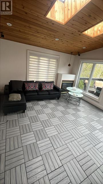 Newmarket (Huron Heights-Leslie Valley) apartment for rent - A living room with a black couch and a wooden ceiling.
