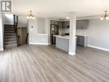 Hamilton townhouse for rent - A spacious kitchen and living room with wood flooring and a staircase.
