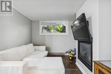 Kitchener triplex for rent - A living room with a white couch and a flat screen TV mounted on the wall.