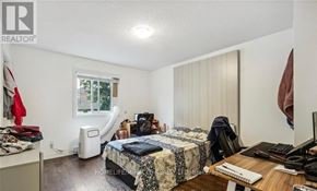 Kitchener triplex for rent - A bedroom with a bed, desk, and window.