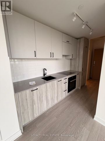 Toronto (Banbury-Don Mills) condo for rent - A kitchen with white cabinets and a wooden floor.