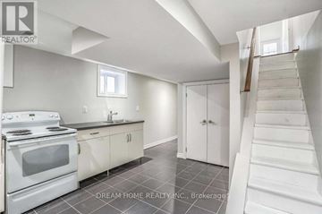 Toronto (Trinity-Bellwoods) apartment for rent - A white kitchen with a stove top oven and a staircase.