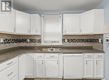 St. Catharines (E. Chester) apartment for rent - A kitchen with white cabinets and a checkered backsplash.
