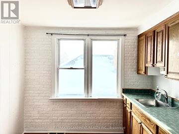 Welland (Lincoln/Crowland) triplex for rent - A kitchen with a white brick wall and wooden cabinets.