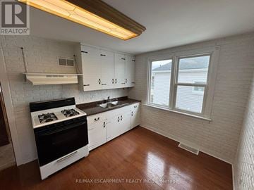 Welland (Lincoln/Crowland) triplex for rent - A kitchen with white cabinets and a black stove top oven.