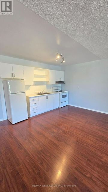 Innisfil multi-family for rent - A kitchen with white appliances and wooden floors.