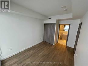 Toronto (Bayview Village) condo for rent - A room with wooden flooring and white walls, with a doorway leading to another room.