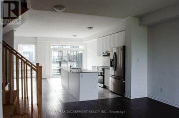 Oakville (Ga Glen Abbey) townhouse for rent - A kitchen with white cabinets and a stainless steel refrigerator.