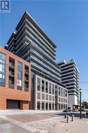 Hamilton (Beasley) condo for rent - A modern multi-story building with a glass facade stands next to a red brick building.