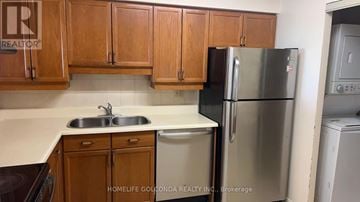 Toronto (Steeles) condo for rent - A kitchen with wooden cabinets and a stainless steel refrigerator.