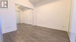 Markham (Unionville) condo for rent - A room with a wooden floor and white walls, with a glass door leading to another room.