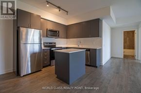 Barrie (Little Lake) condo for rent - A modern kitchen with a refrigerator, microwave, and oven.