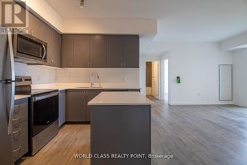 Barrie (Little Lake) condo for rent - A modern kitchen with dark brown cabinets and stainless steel appliances.