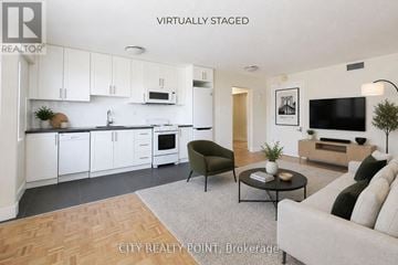 Toronto (Yonge-St. Clair) condo for rent - A modern kitchen with white cabinets and a dining area with a black table.