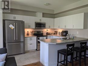 Collingwood townhouse for rent - A kitchen with a refrigerator, microwave, oven, and sink.