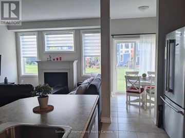 Collingwood townhouse for rent - A kitchen with a stove top oven and a dining table with chairs.