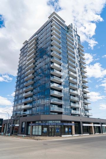 Edmonton apartment for rent - A tall building with many windows and balconies is under a blue sky with clouds.