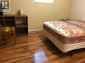 Calgary apartment for rent - A bedroom with a bed, nightstand, and chair.