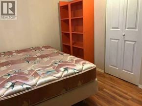 Calgary apartment for rent - A bed with a floral print mattress pad sits in a room with a white door and a wooden floor.
