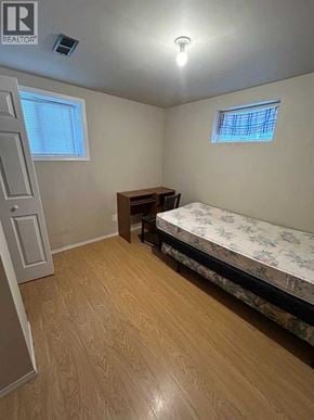 Calgary apartment for rent - A bedroom with a bed, desk, and window.