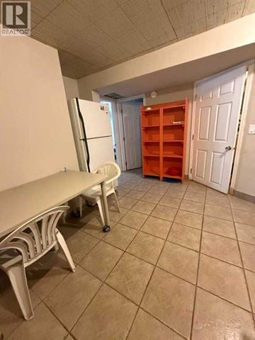 Calgary apartment for rent - A kitchen area with a white fridge, orange shelves, and a white table.