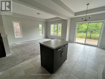Niagara Falls (Cherrywood) townhouse for rent - A spacious room with a kitchen island and sliding glass doors leading to a green outdoor area.