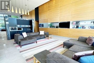 Toronto (Banbury-Don Mills) condo for rent - A modern living room with a grey couch and a wooden wall.