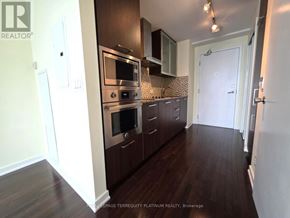Toronto (Waterfront Communities) condo for rent - A kitchen with dark wood floors and white walls.