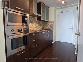 Toronto (Waterfront Communities) condo for rent - A kitchen with dark wood cabinets and stainless steel appliances.