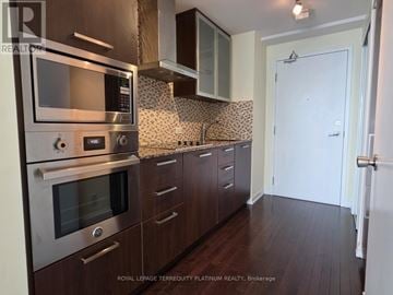 Toronto (Waterfront Communities) condo for rent - A kitchen with dark wood cabinets and stainless steel appliances.
