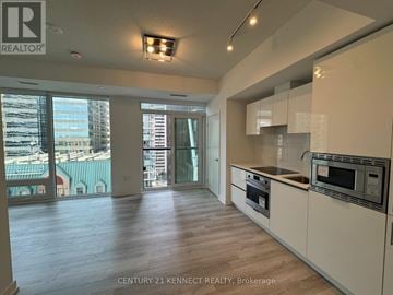 Toronto (Kensington-Chinatown) condo for rent - A kitchen with white cabinets and a wooden floor.